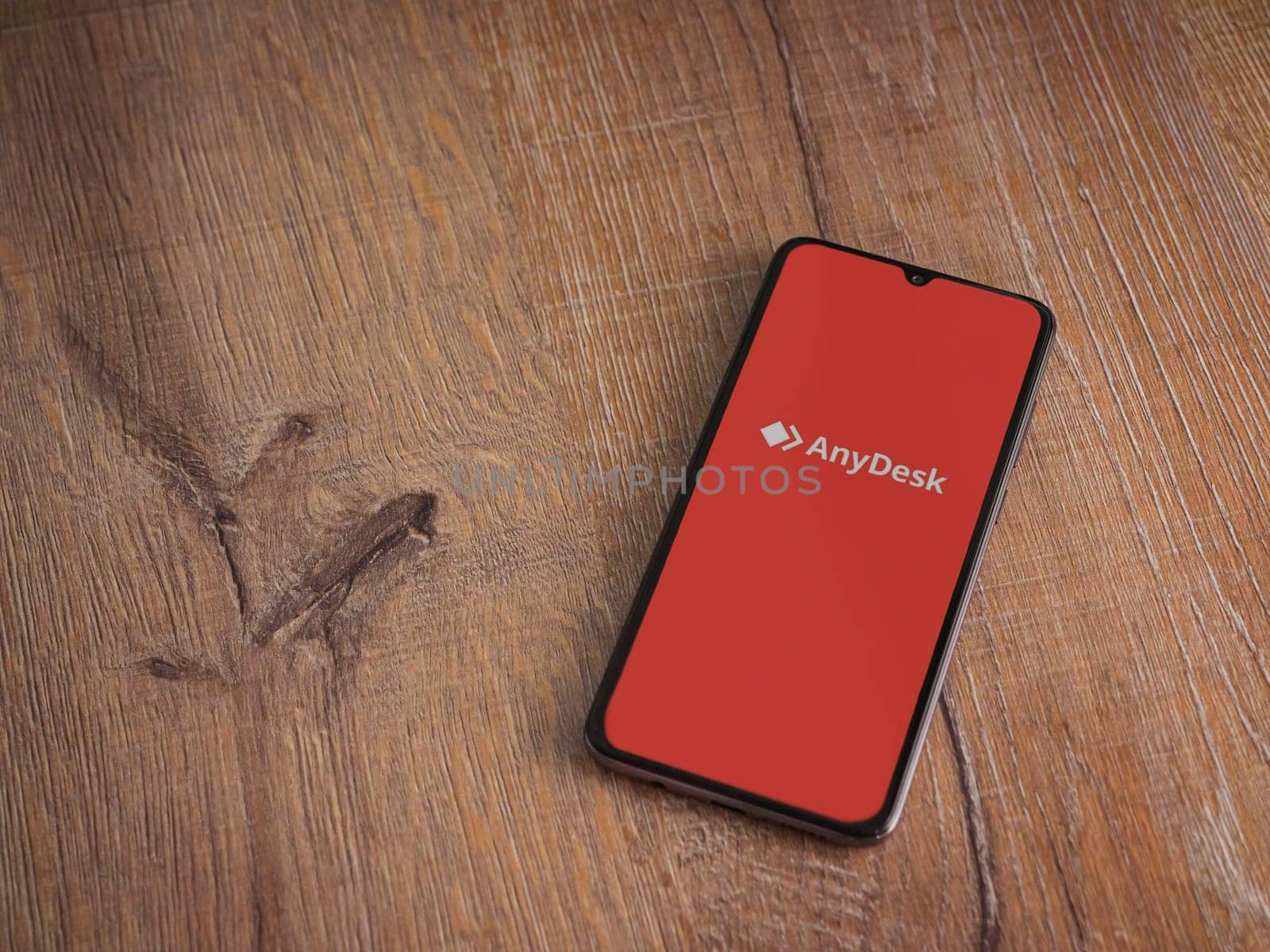 Lod, Israel - July 16,2023: Anydesk app launch screen on smartphone on wooden background. Top view flat lay with copy space.