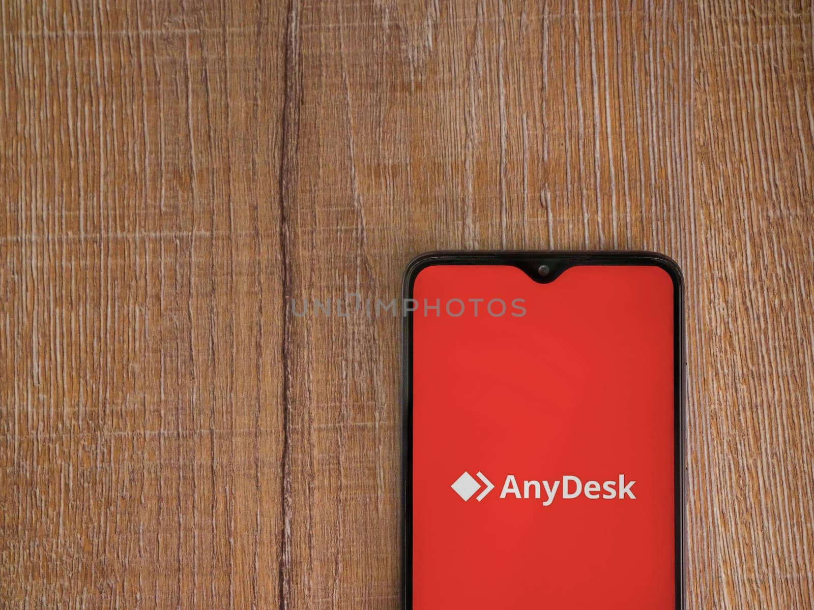 Lod, Israel - July 16,2023: Anydesk app launch screen on smartphone on wooden background. Top view flat lay with copy space.