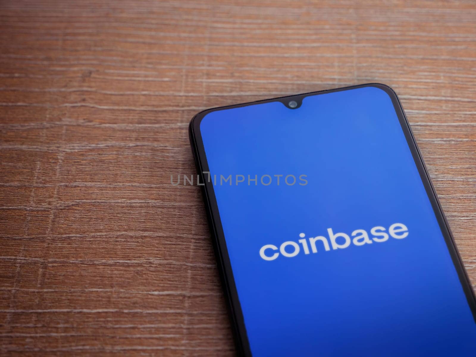 Lod, Israel - July 16,2023: Coinbase app launch screen on smartphone on wooden background. Top view flat lay with copy space.