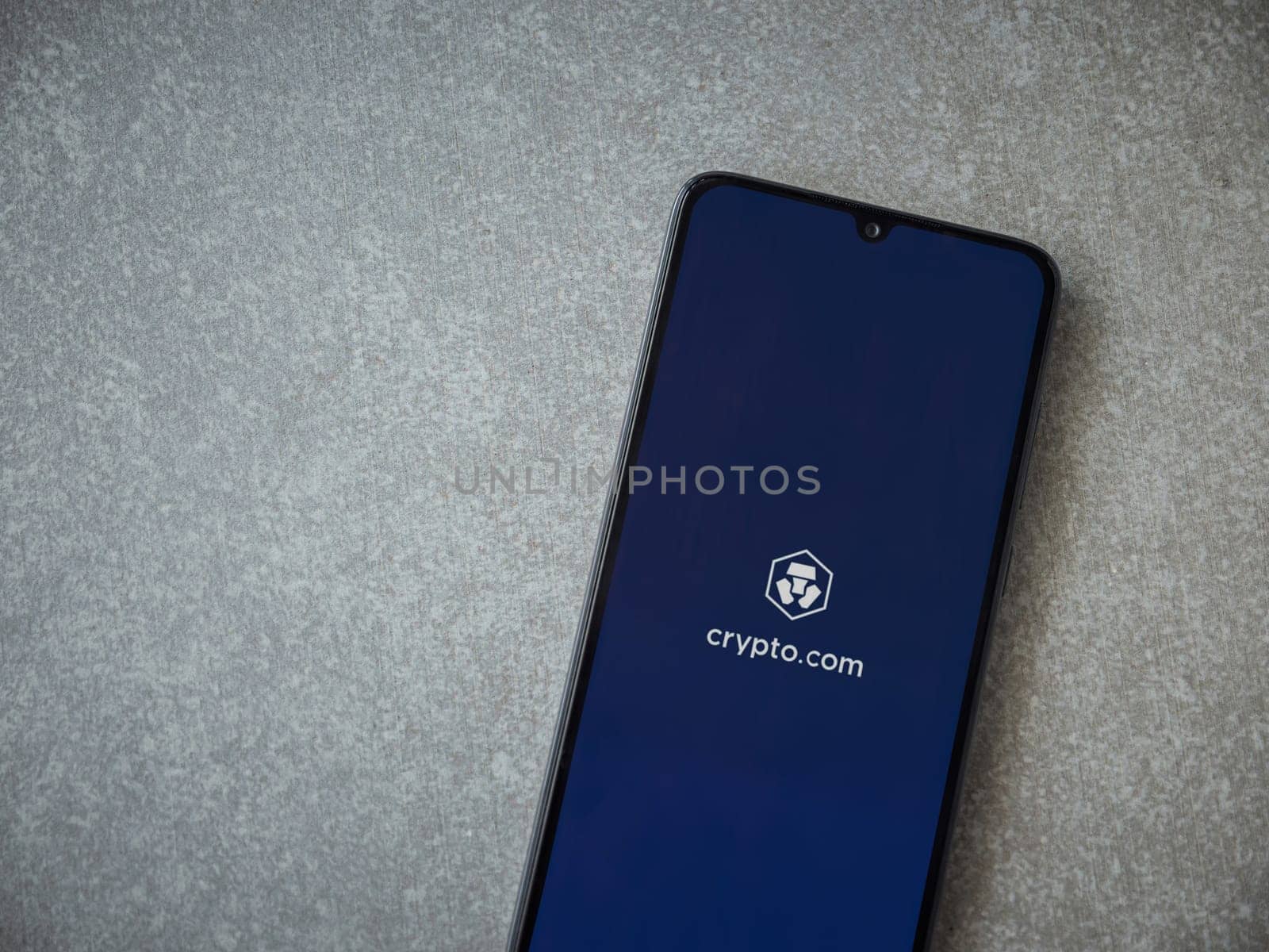 Lod, Israel - July 16,2023: Crypto.com app launch screen on smartphone on ceramic stone background. Top view flat lay with copy space.