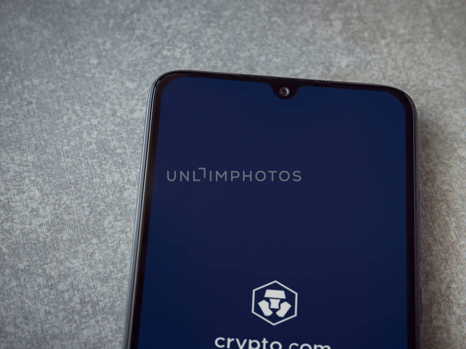 Lod, Israel - July 16,2023: Crypto.com app launch screen on smartphone on ceramic stone background. Top view flat lay with copy space.