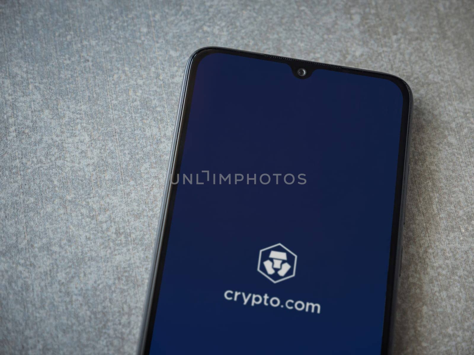 Lod, Israel - July 16,2023: Crypto.com app launch screen on smartphone on ceramic stone background. Top view flat lay with copy space.