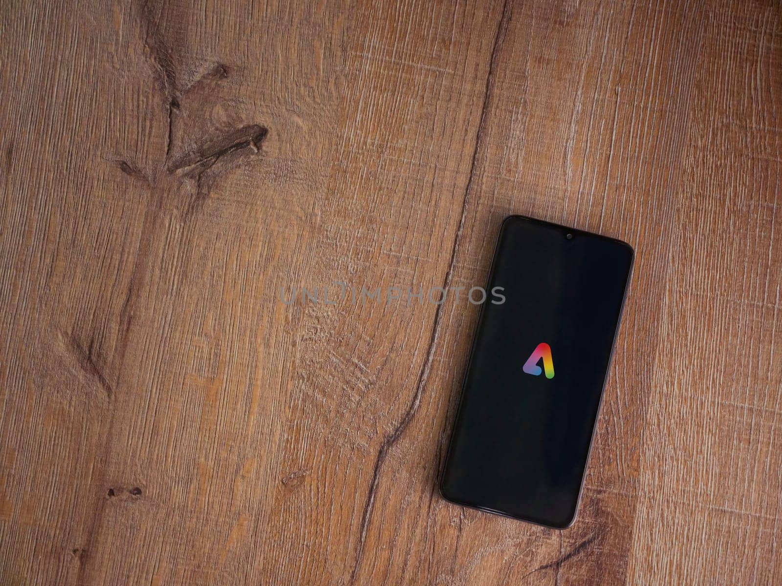 Lod, Israel - July 16,2023: Adobe Express - Graphic Design app launch screen on smartphone on wooden background.. Top view flat lay with copy space.