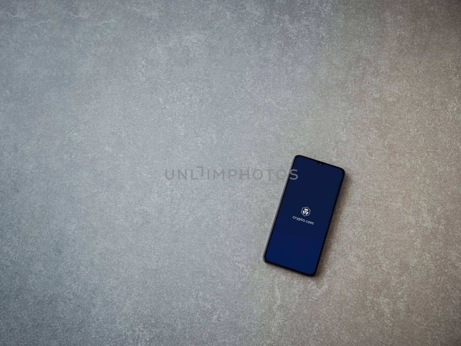 Lod, Israel - July 16,2023: Crypto.com app launch screen on smartphone on ceramic stone background. Top view flat lay with copy space.