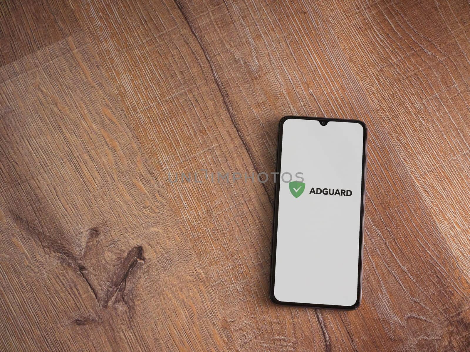 Lod, Israel - July 16,2023: AdGuard app launch screen on smartphone on wooden background. Top view flat lay with copy space.