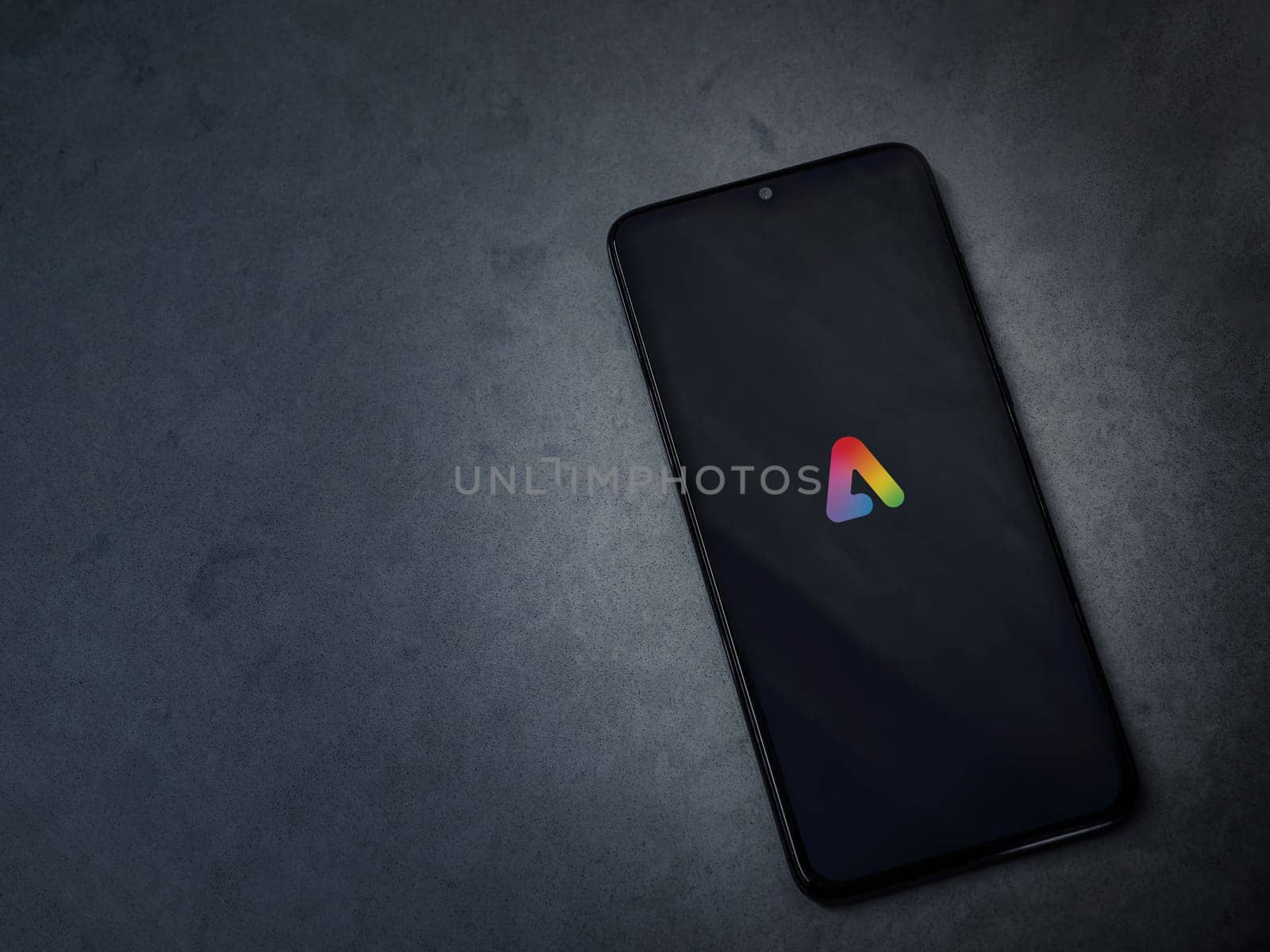 Lod, Israel - July 16,2023: Adobe Express - Graphic Design app launch screen on smartphone on dark marble stone background. Top view flat lay with copy space.