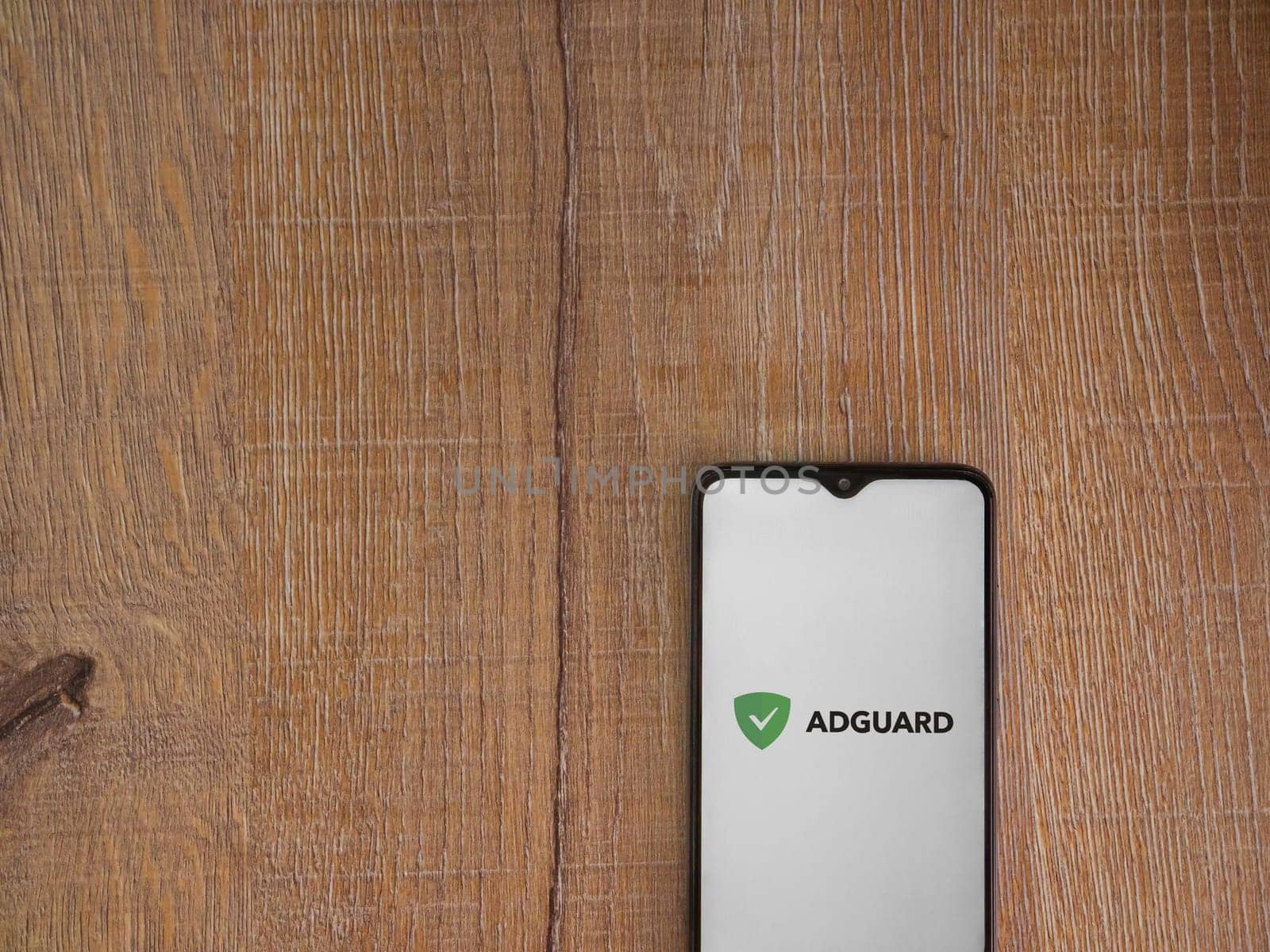 Lod, Israel - July 16,2023: AdGuard app launch screen on smartphone on wooden background. Top view flat lay with copy space.