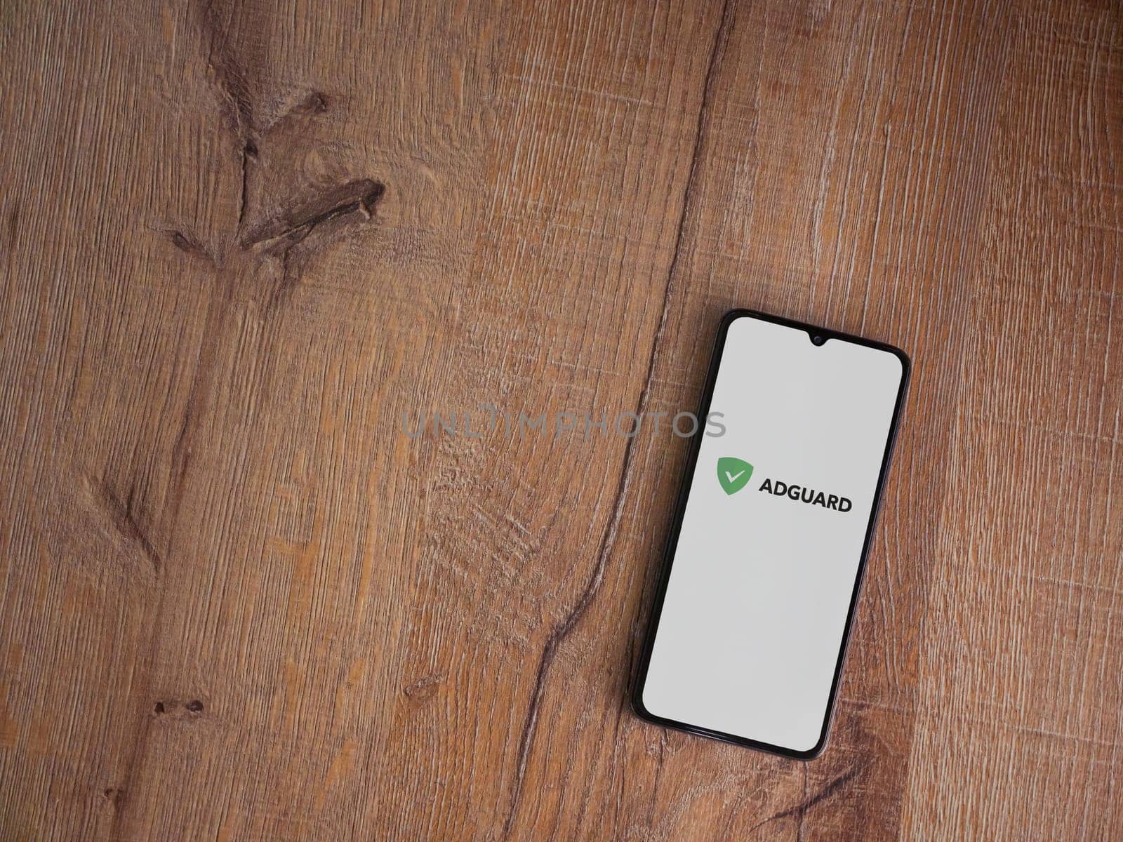 Lod, Israel - July 16,2023: AdGuard app launch screen on smartphone on wooden background. Top view flat lay with copy space.