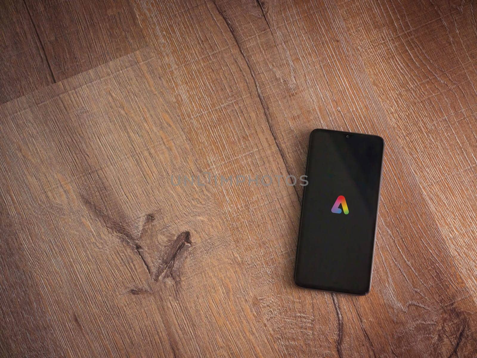 Lod, Israel - July 16,2023: Adobe Express - Graphic Design app launch screen on smartphone on wooden background. Top view flat lay with copy space.