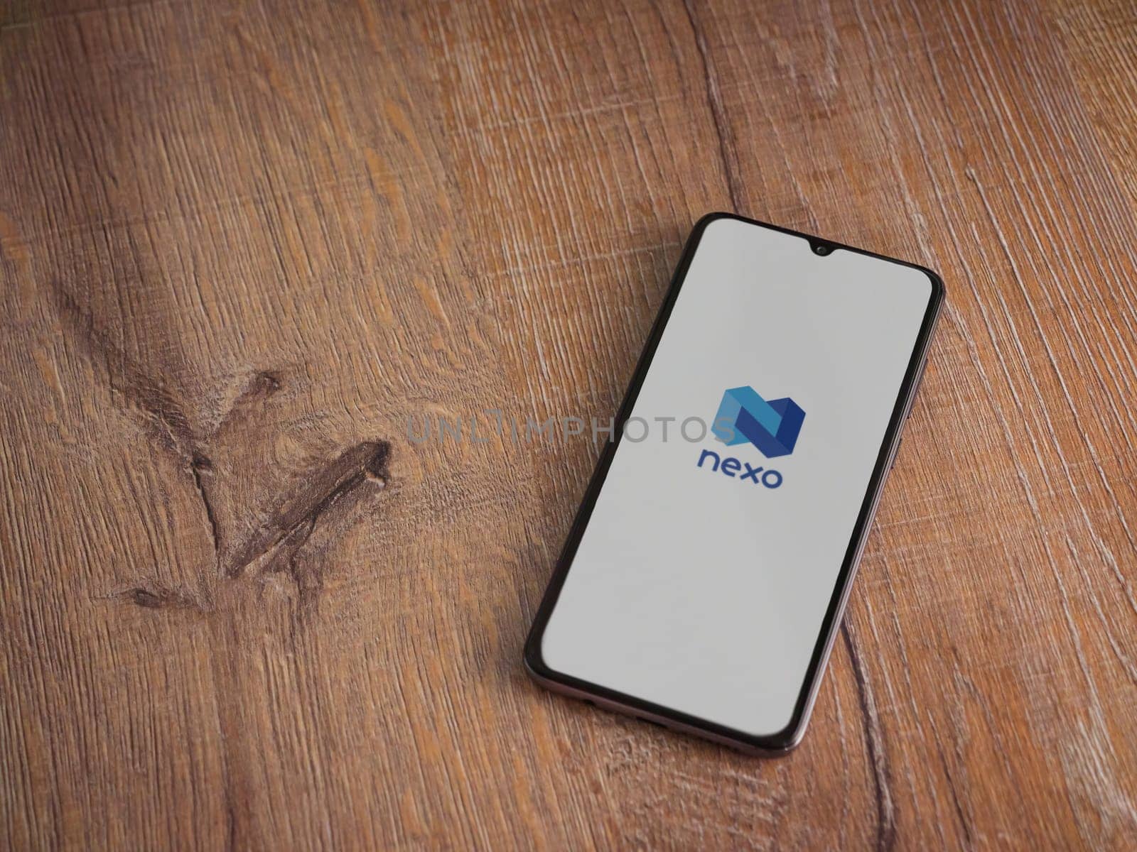 Lod, Israel - July 16,2023: Nexo app launch screen on smartphone on wooden background. Top view flat lay with copy space.