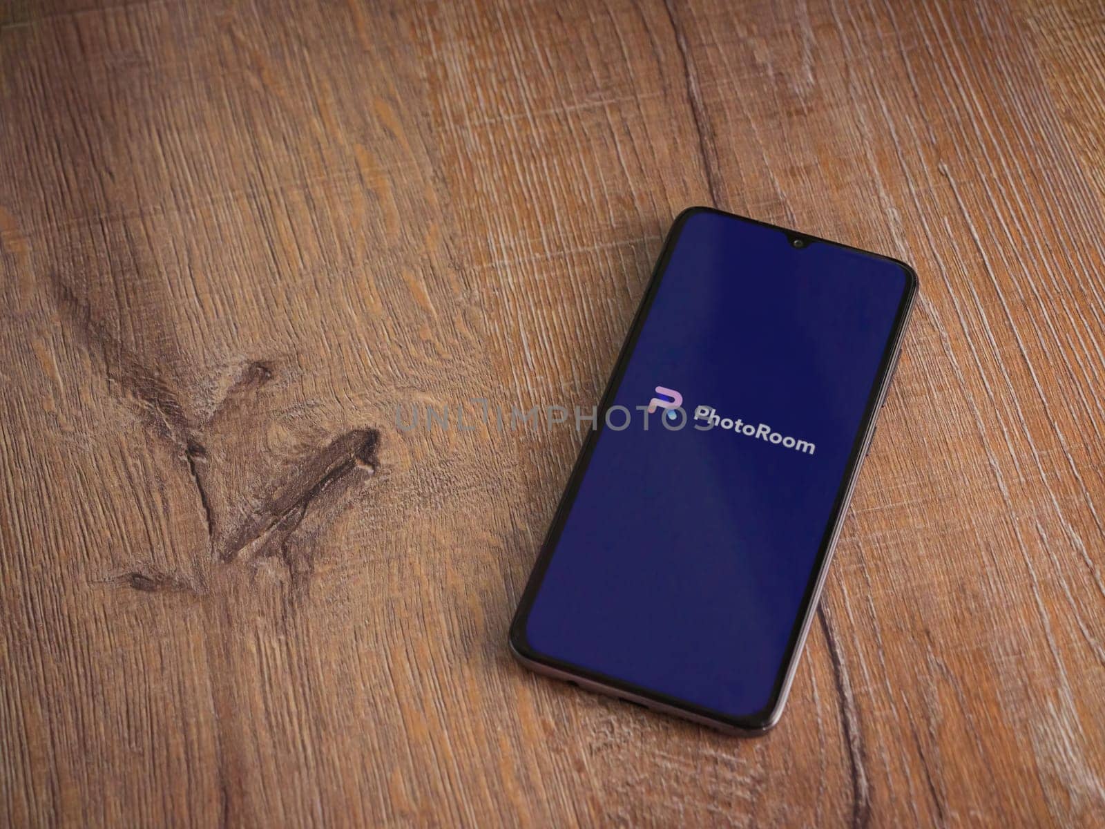 Lod, Israel - July 16,2023: PhotoRoom Studio Photo Editor app launch screen on smartphone on wooden background.. Top view flat lay with copy space.