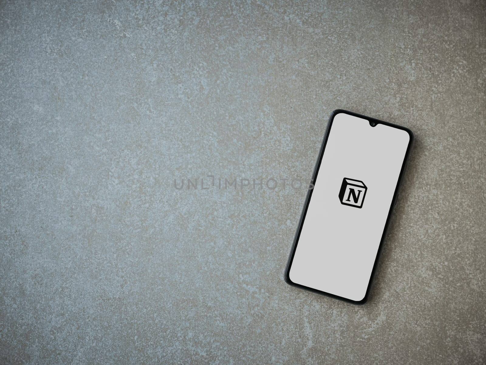 Lod, Israel - July 16,2023: Notion app launch screen on smartphone on ceramic stone background. Top view flat lay with copy space.