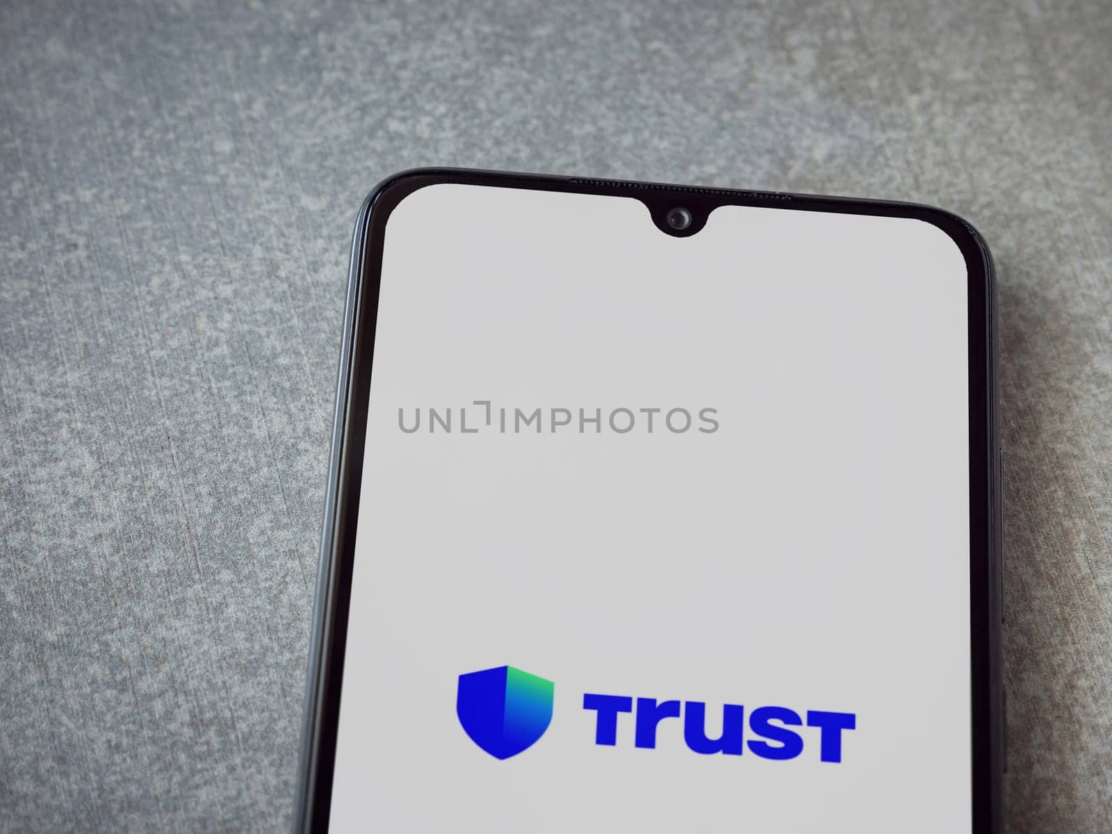 Lod, Israel - July 16,2023: Trust Wallet app launch screen on smartphone on ceramic stone background. Top view flat lay with copy space.