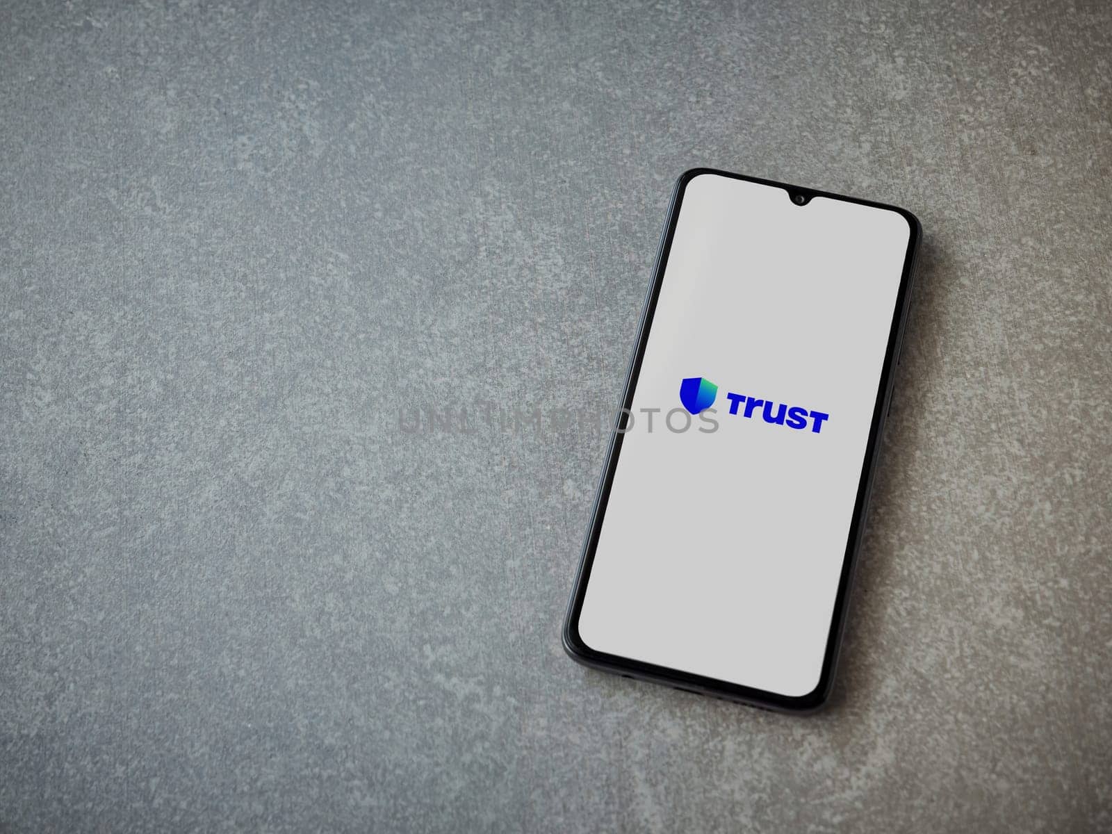 Lod, Israel - July 16,2023: Trust Wallet app launch screen on smartphone on ceramic stone background. Top view flat lay with copy space.