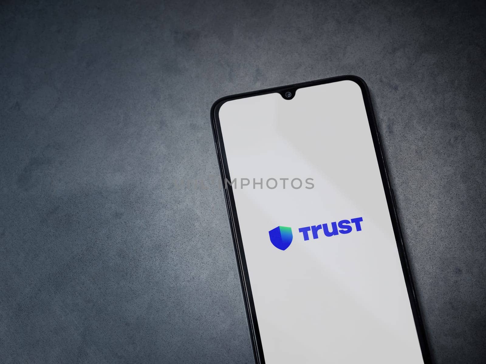 Lod, Israel - July 16,2023: Trust Wallet app launch screen on smartphone on dark marble stone background. Top view flat lay with copy space.