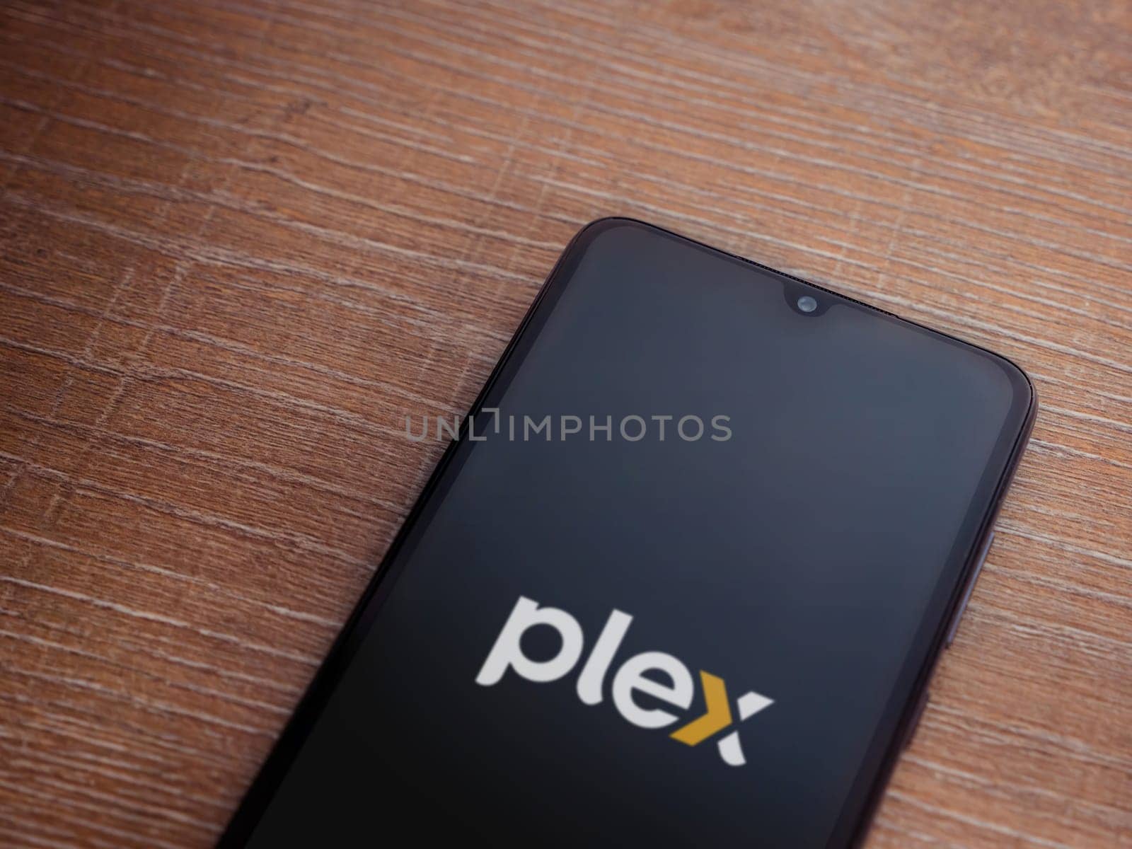 Lod, Israel - July 16,2023: Plex app launch screen on smartphone on wooden background. Top view flat lay with copy space.