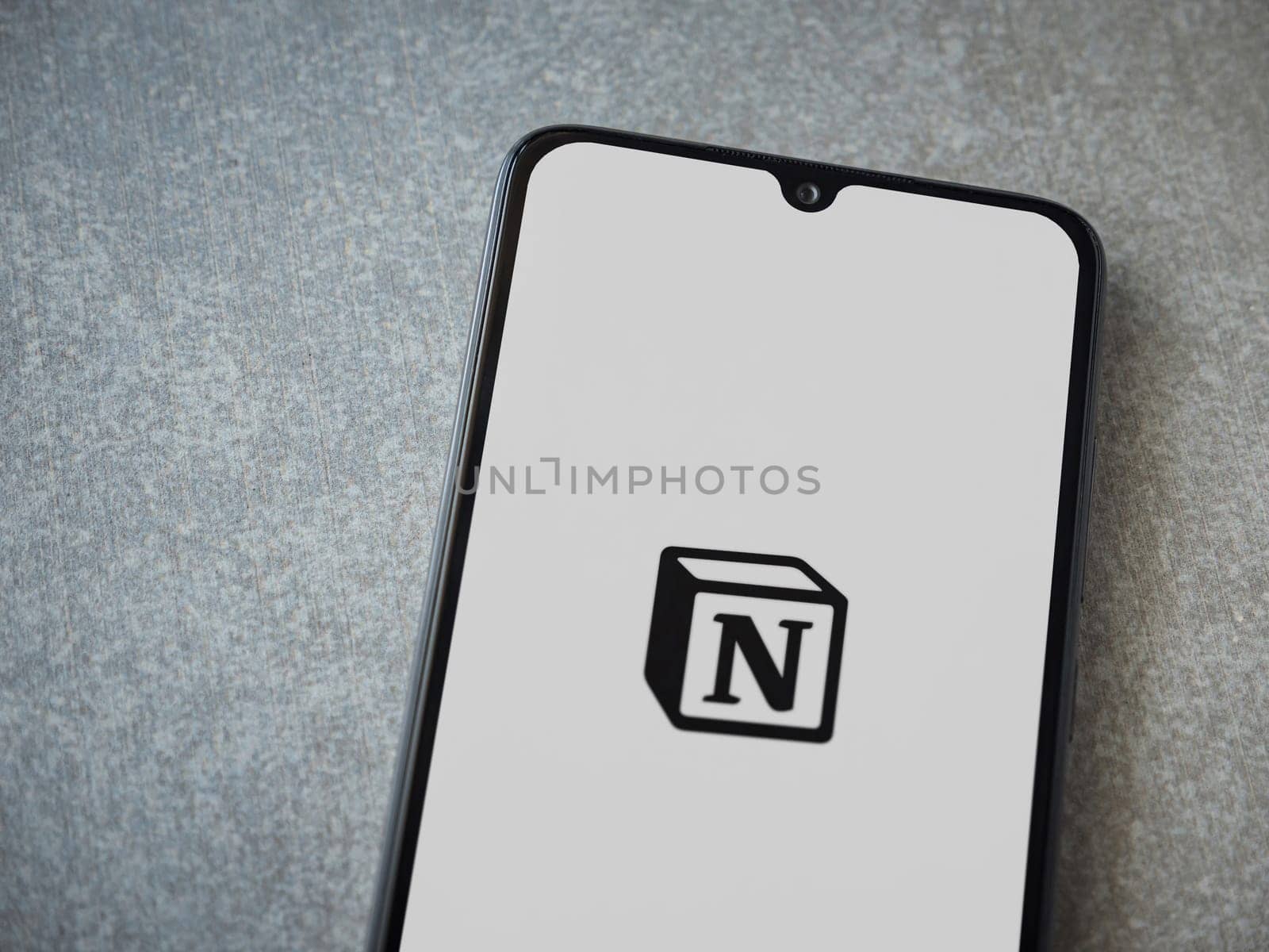 Lod, Israel - July 16,2023: Notion app launch screen on smartphone on ceramic stone background. Top view flat lay with copy space.