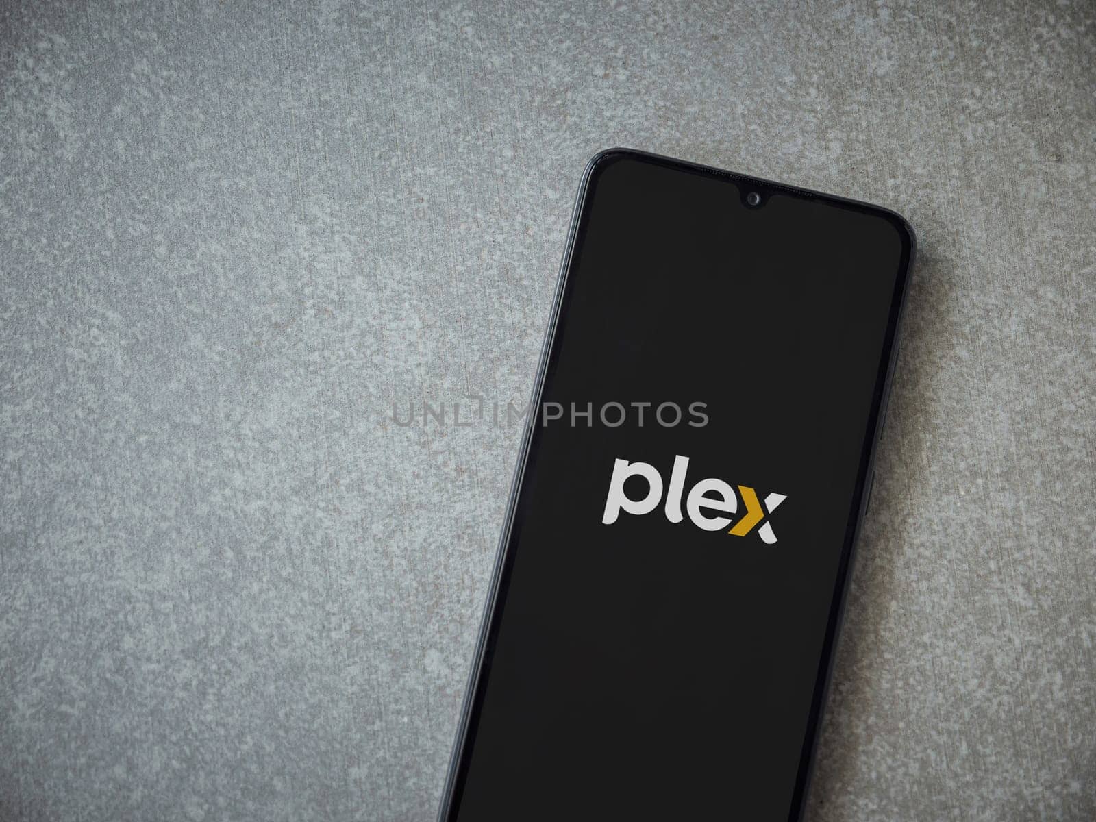Lod, Israel - July 16,2023: Plex app launch screen on smartphone on ceramic stone background. Top view flat lay with copy space.