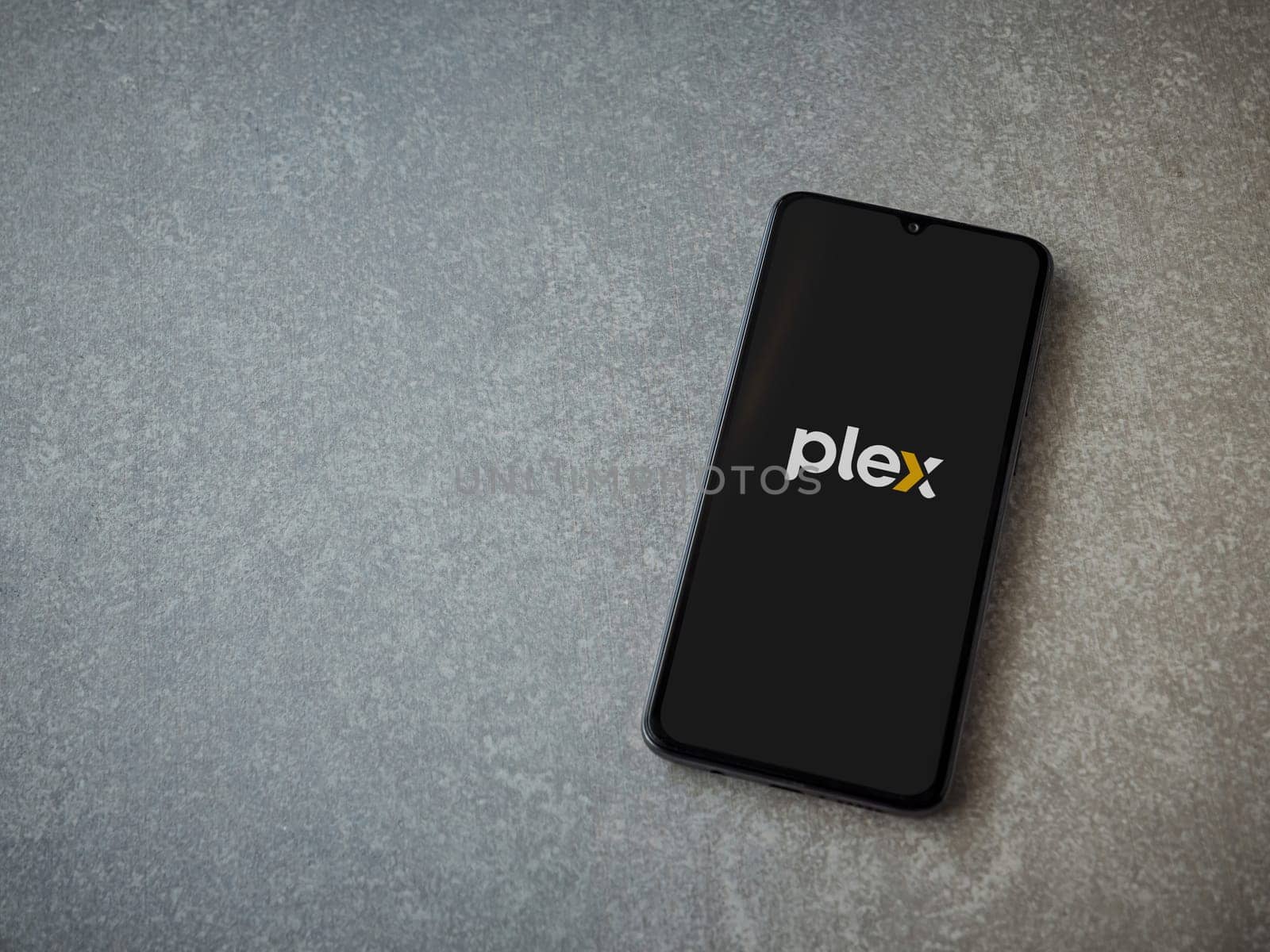 Lod, Israel - July 16,2023: Plex app launch screen on smartphone on ceramic stone background. Top view flat lay with copy space.