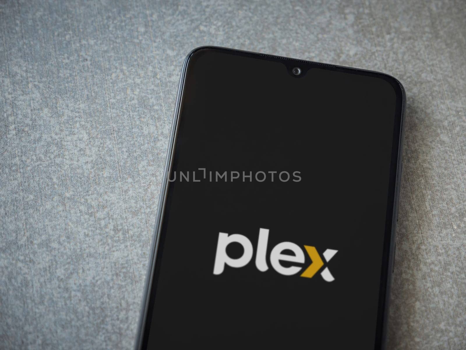 Lod, Israel - July 16,2023: Plex app launch screen on smartphone on ceramic stone background. Top view flat lay with copy space.