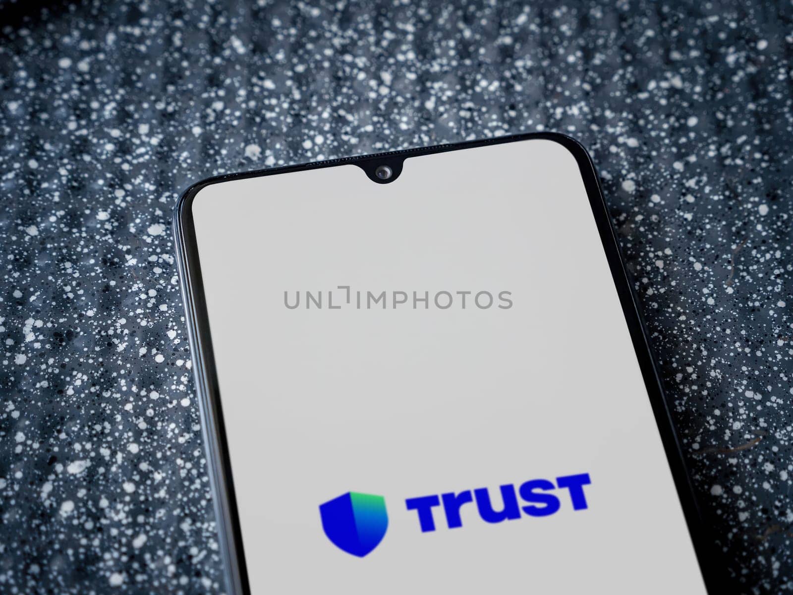 Lod, Israel - July 16,2023: Trust Wallet app launch screen on smartphone on metallic background. Close up top view flat lay.