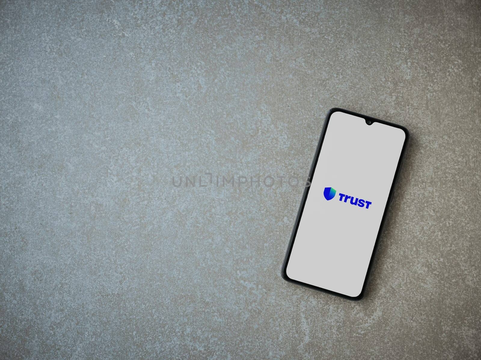Lod, Israel - July 16,2023: Trust Wallet app launch screen on smartphone on ceramic stone background. Top view flat lay with copy space.