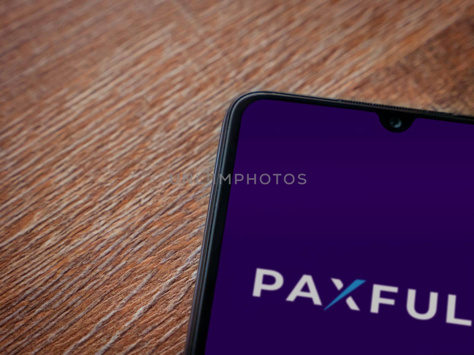 Lod, Israel - July 16,2023: Paxful app launch screen on smartphone on wooden background. Top view flat lay with copy space.