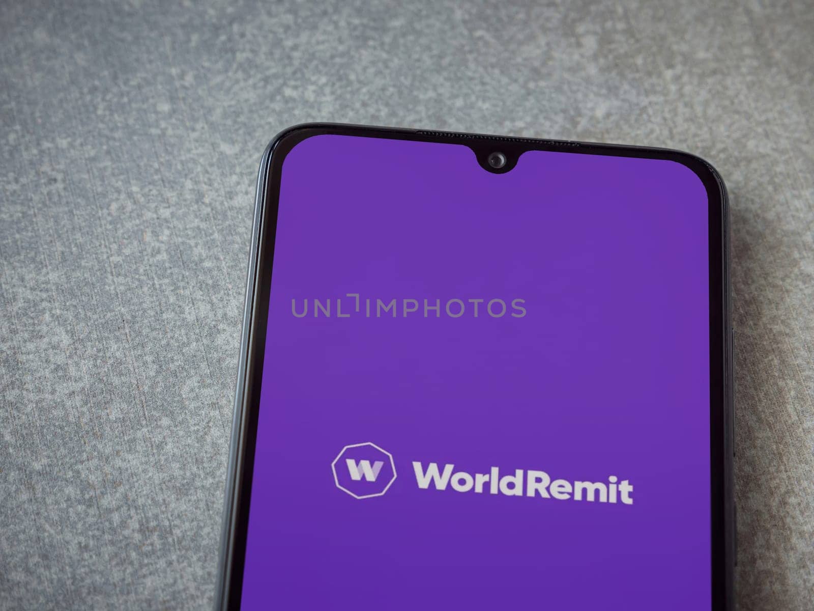 Lod, Israel - July 16,2023: WorldRemit app launch screen on smartphone on ceramic stone background. Top view flat lay with copy space.