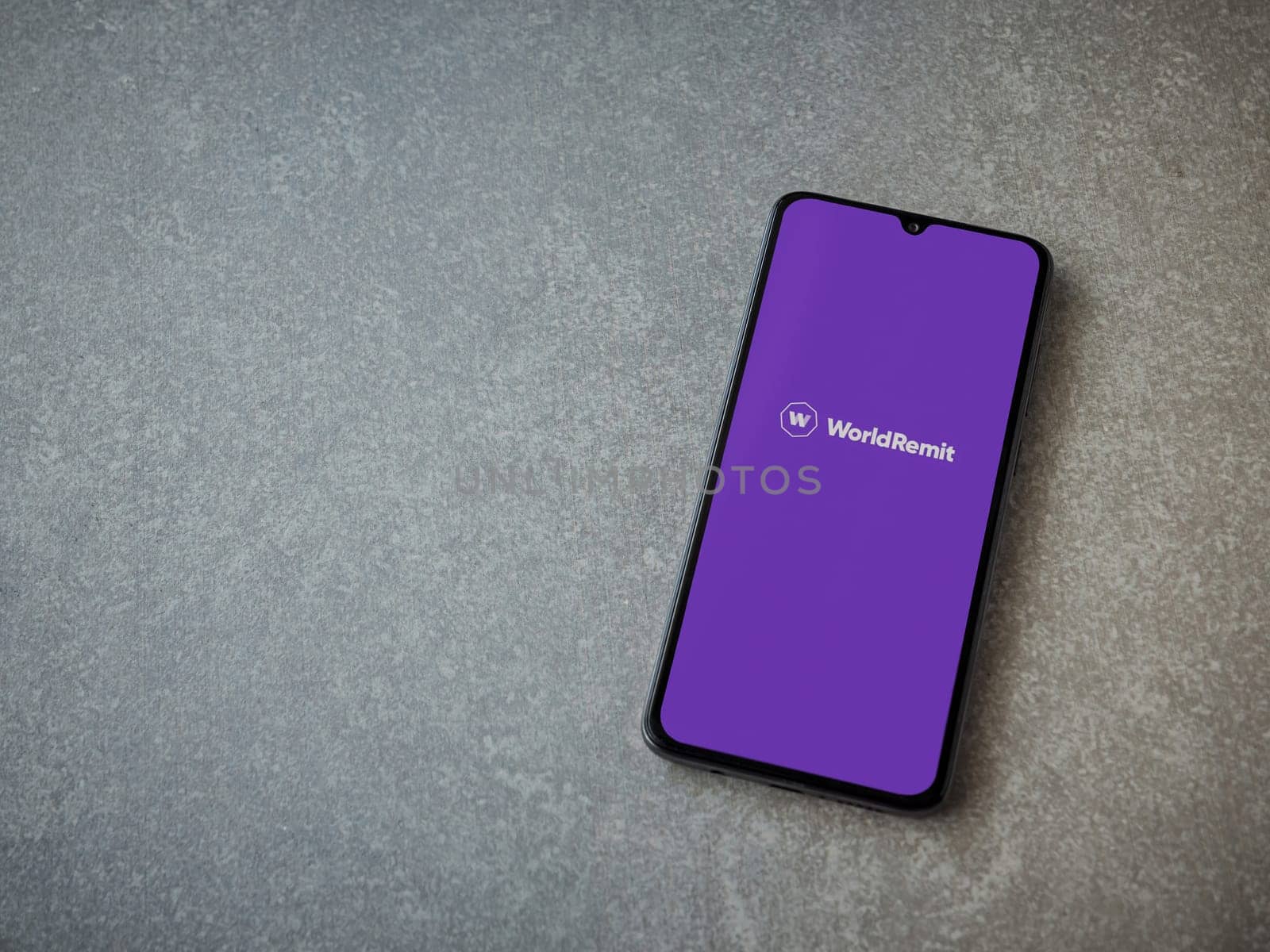 Lod, Israel - July 16,2023: WorldRemit app launch screen on smartphone on ceramic stone background. Top view flat lay with copy space.