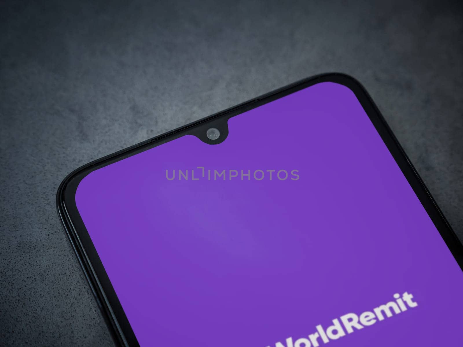 Lod, Israel - July 16,2023: WorldRemit app launch screen on smartphone on dark marble stone background. Top view flat lay with copy space.