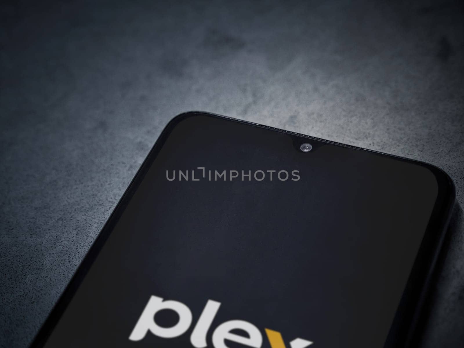 Lod, Israel - July 16,2023: Plex app launch screen on smartphone on dark marble stone background. Top view flat lay with copy space.
