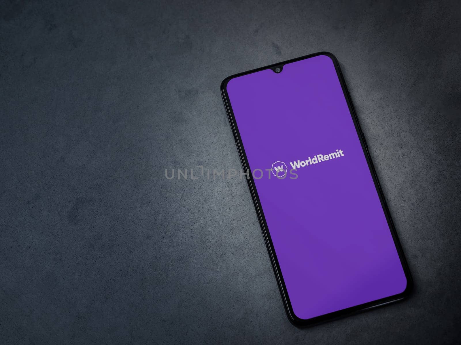 Lod, Israel - July 16,2023: WorldRemit app launch screen on smartphone on dark marble stone background. Top view flat lay with copy space.