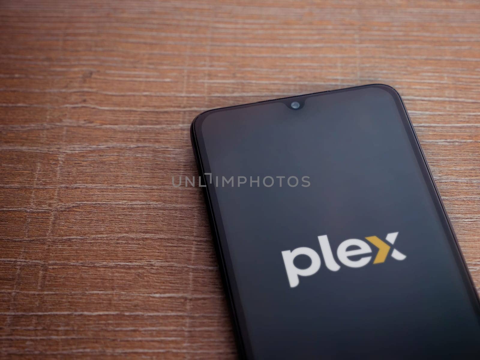 Lod, Israel - July 16,2023: Plex app launch screen on smartphone on wooden background. Top view flat lay with copy space.