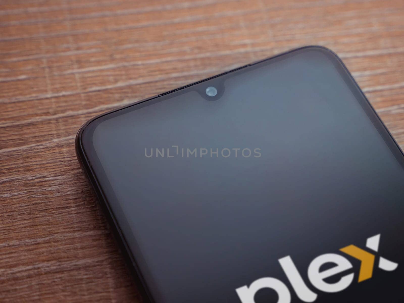 Lod, Israel - July 16,2023: Plex app launch screen on smartphone on wooden background. Top view flat lay with copy space.