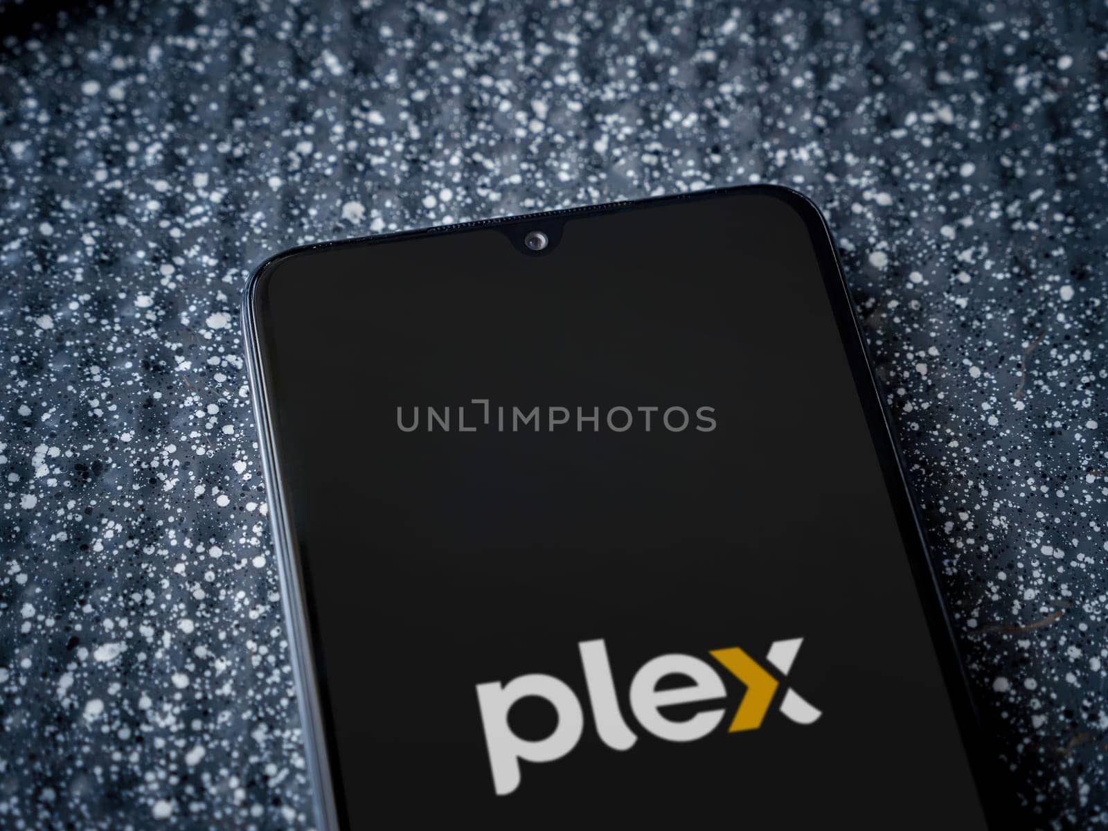Lod, Israel - July 16,2023: Plex app launch screen on smartphone on metallic background. Close up top view flat lay.