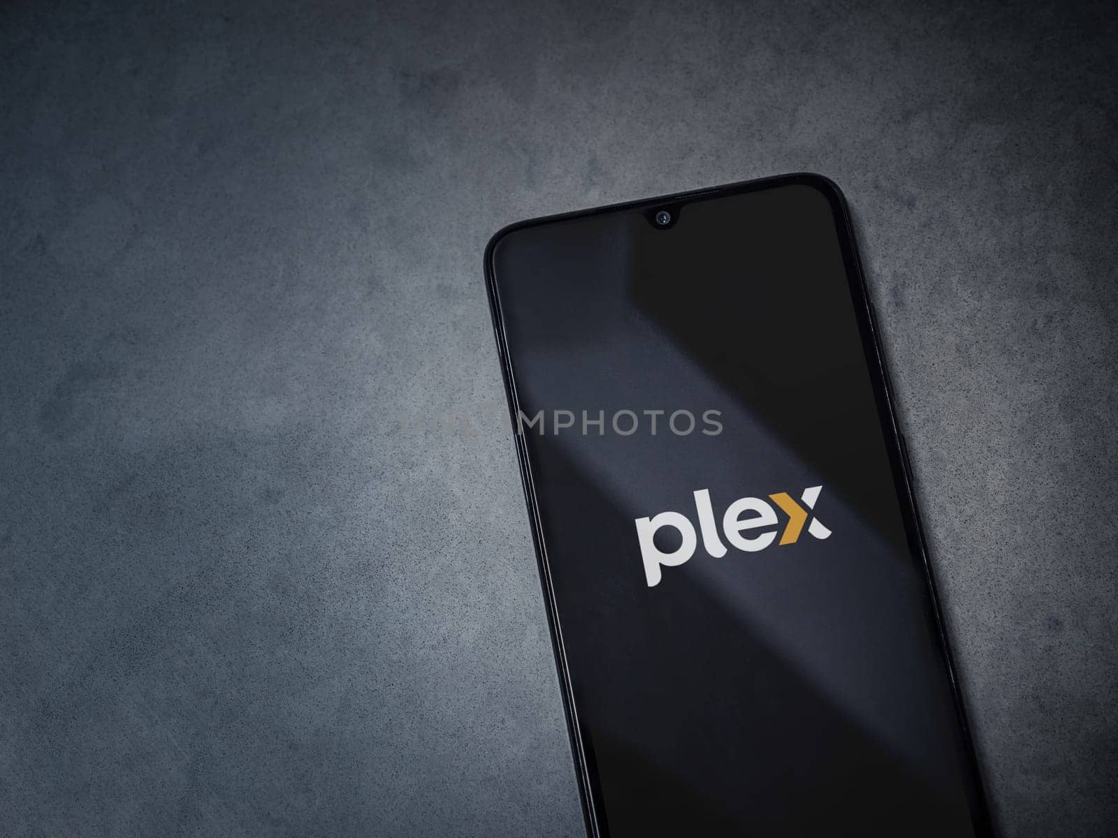 Lod, Israel - July 16,2023: Plex app launch screen on smartphone on dark marble stone background. Top view flat lay with copy space.