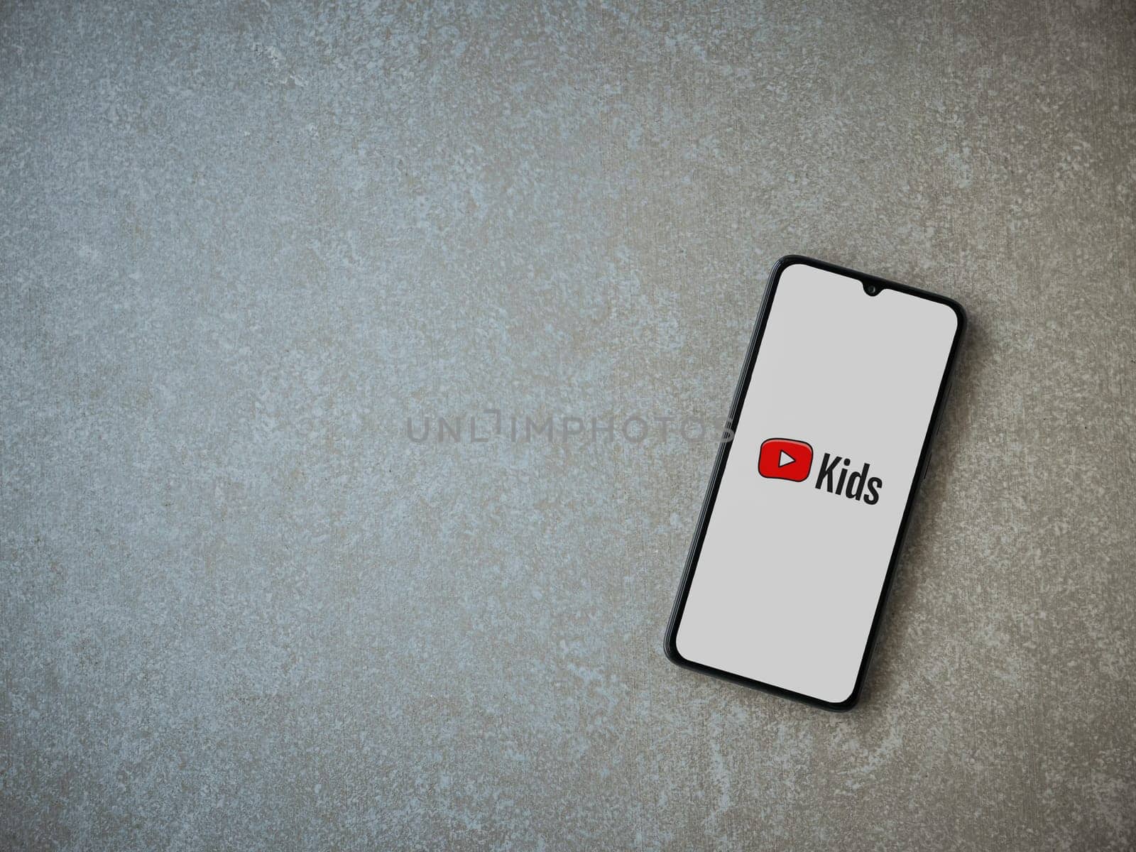 Lod, Israel - July 16,2023: YouTube Kids app launch screen on smartphone on ceramic stone background. Top view flat lay with copy space.