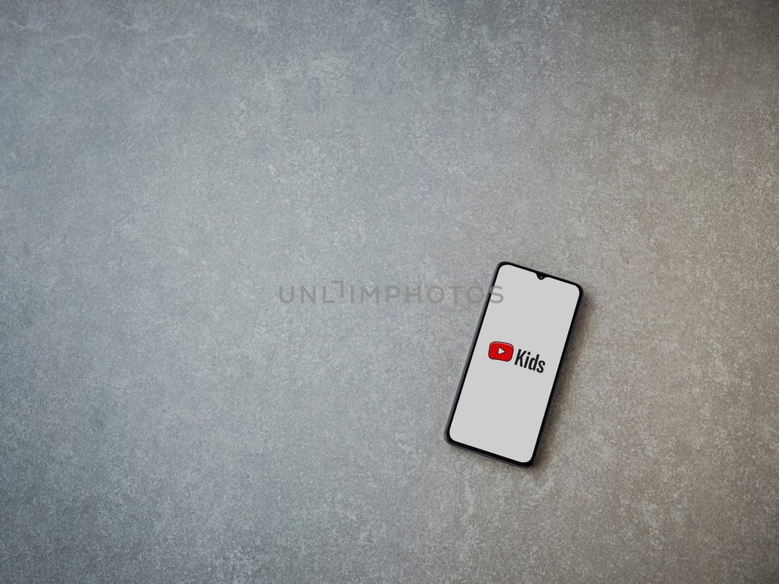 Lod, Israel - July 16,2023: YouTube Kids app launch screen on smartphone on ceramic stone background. Top view flat lay with copy space.