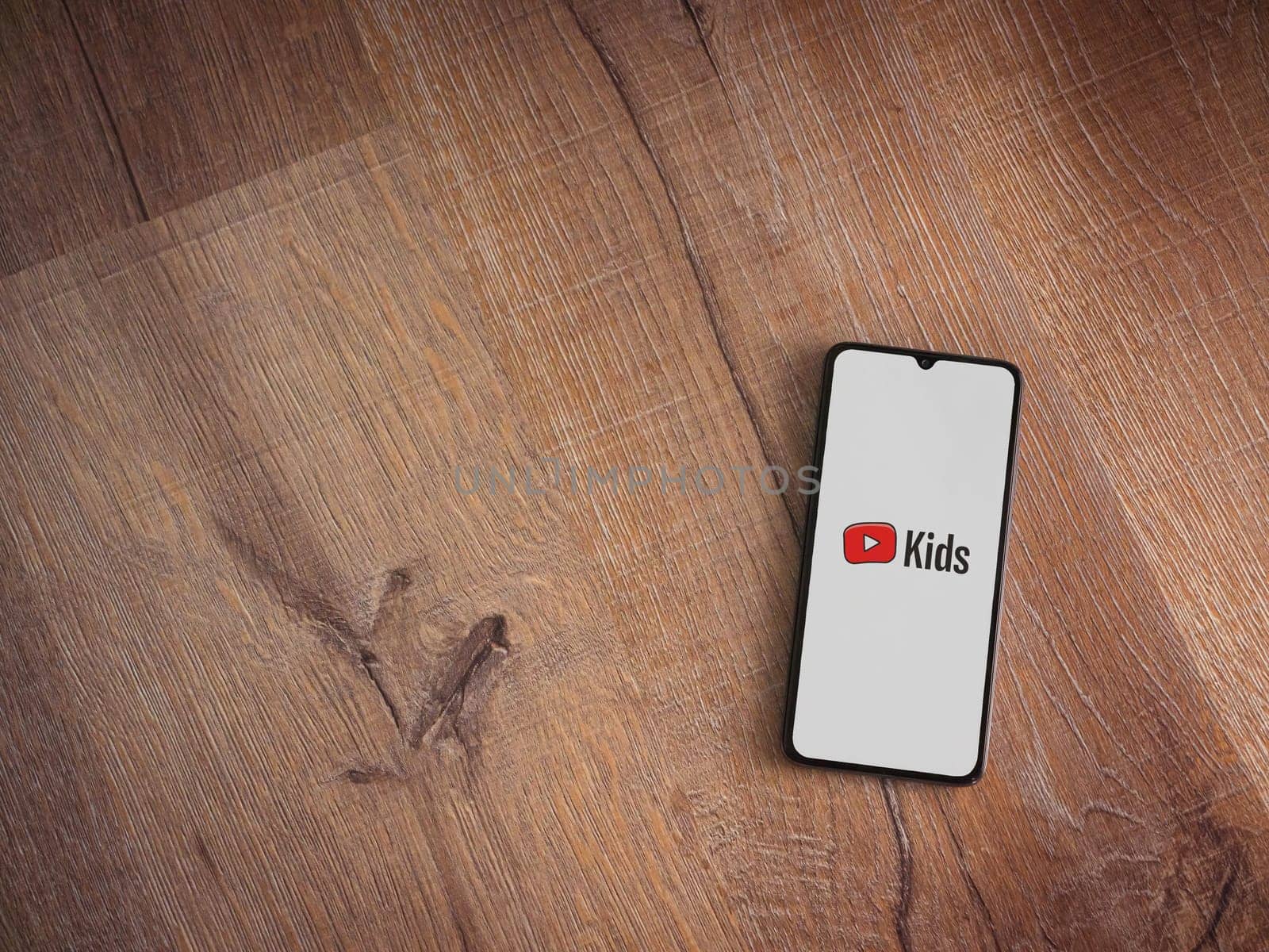 Lod, Israel - July 16,2023: YouTube Kids app launch screen on smartphone on wooden background. Top view flat lay with copy space.