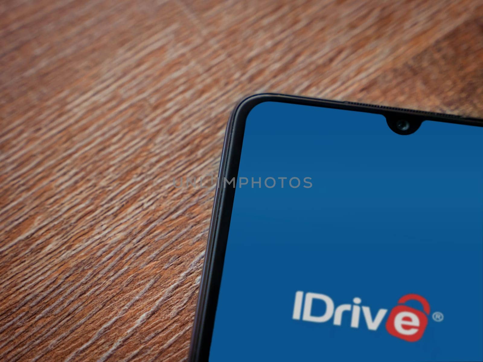 Lod, Israel - July 16,2023: IDrive Online Backup app launch screen on smartphone on wooden background. Top view flat lay with copy space.