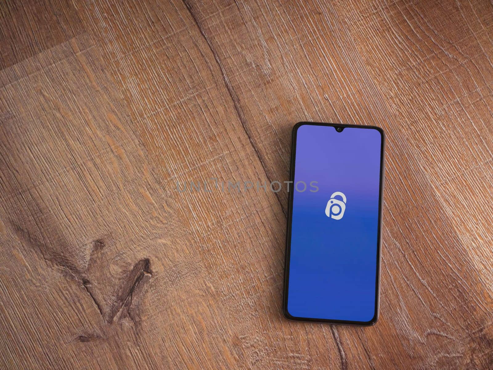 Lod, Israel - July 16,2023: IDrive Photo Backup app launch screen on smartphone on wooden background. Top view flat lay with copy space.