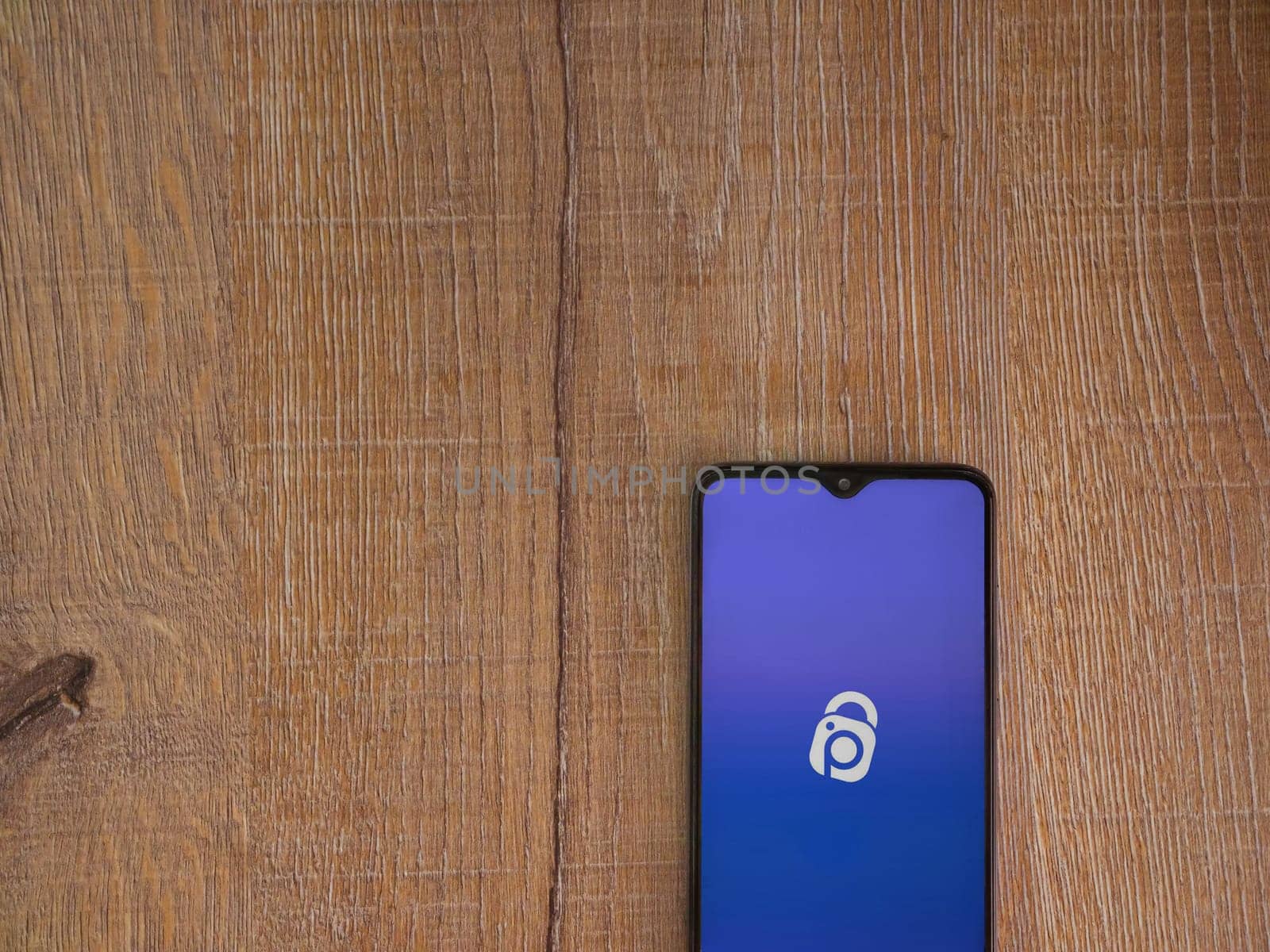 Lod, Israel - July 16,2023: IDrive Photo Backup app launch screen on smartphone on wooden background. Top view flat lay with copy space.