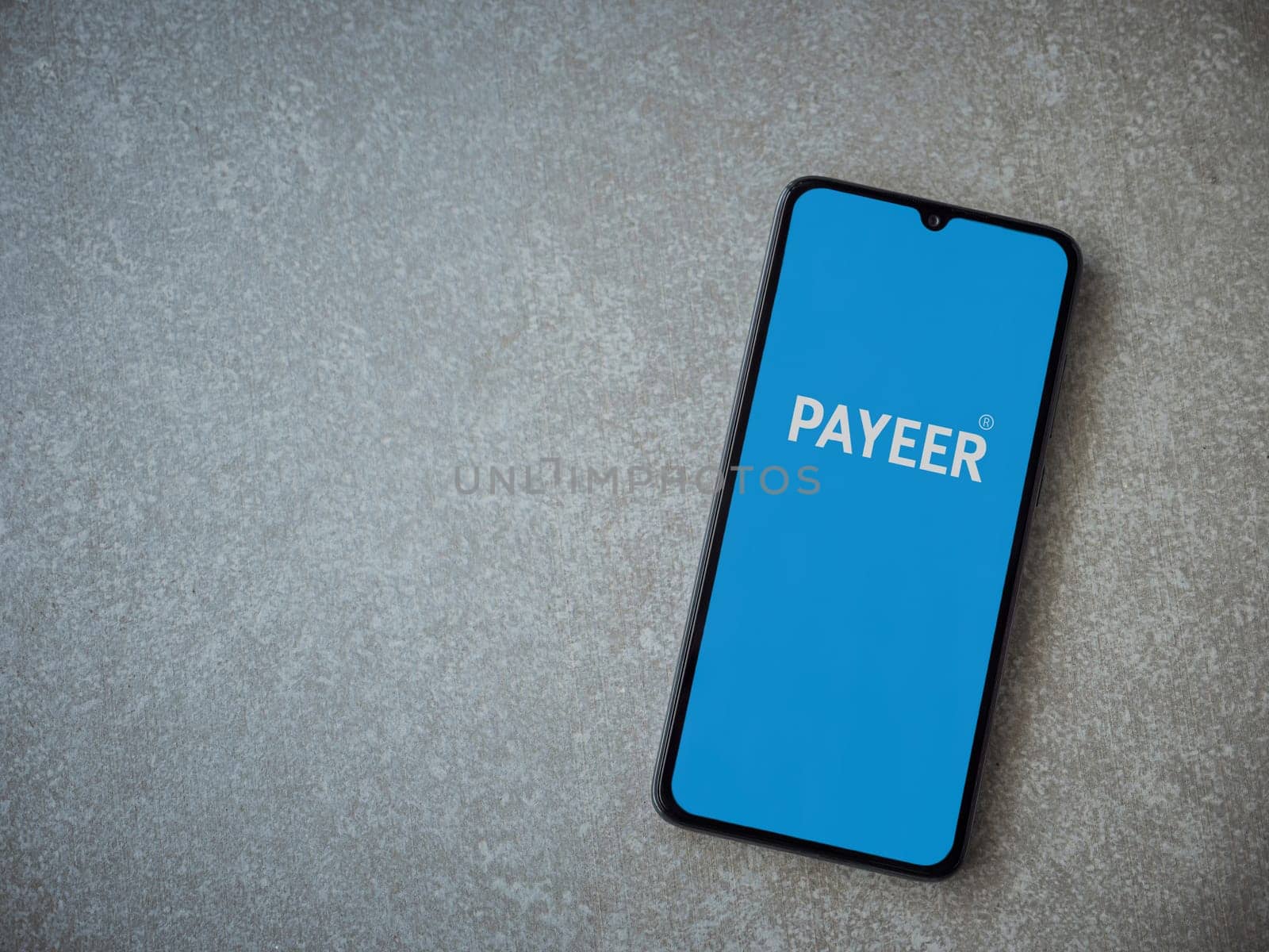 Lod, Israel - July 16,2023: PAYEER app launch screen on smartphone on ceramic stone background. Top view flat lay with copy space.