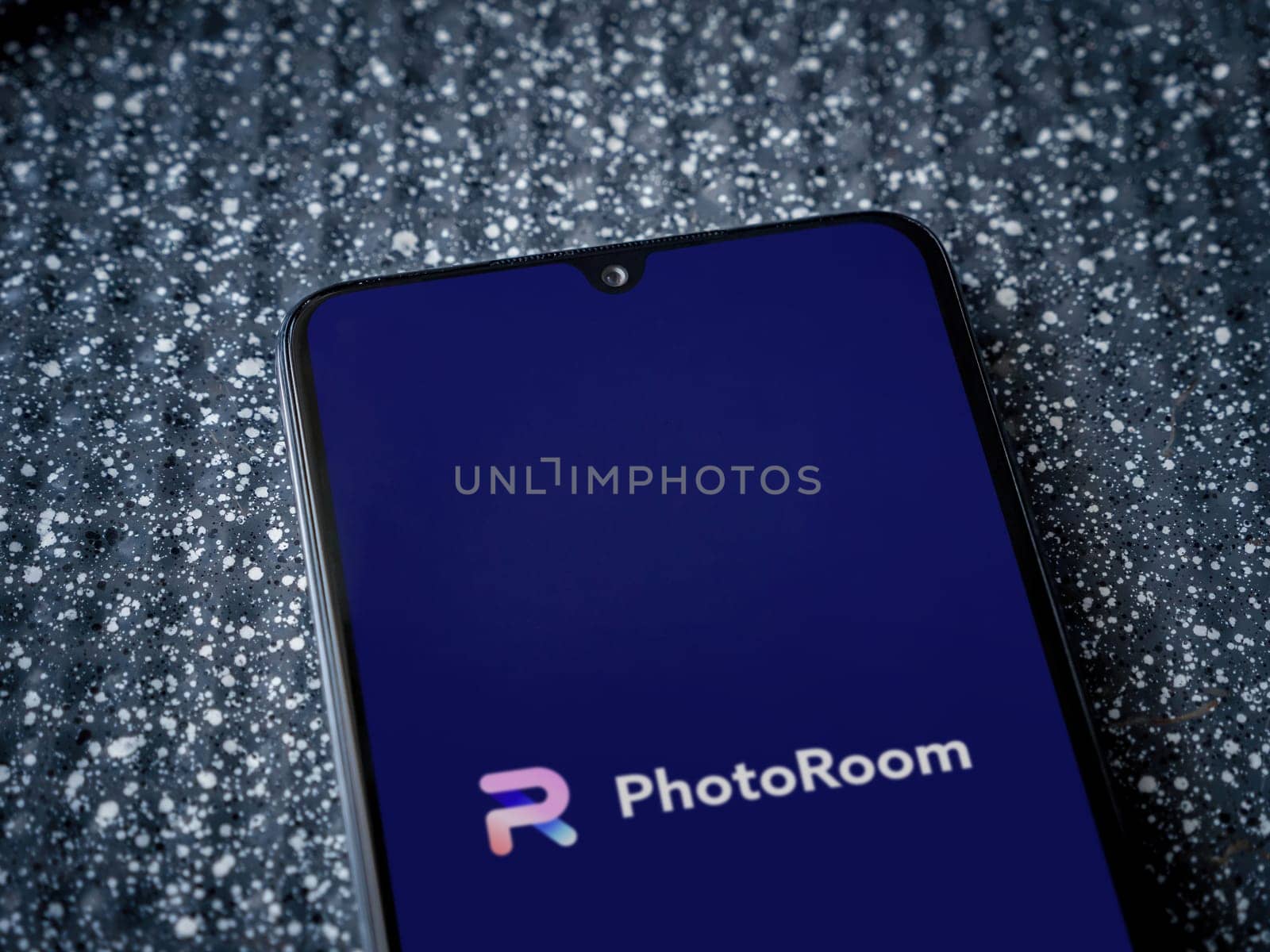 Lod, Israel - July 16,2023: PhotoRoom Studio Photo Editor app launch screen on smartphone on metallic background. Close up top view flat lay.