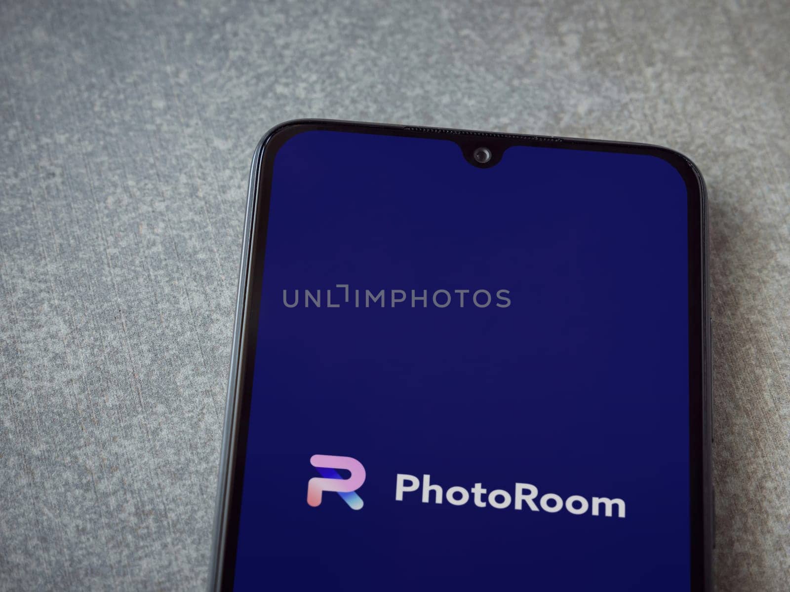 Lod, Israel - July 16,2023: PhotoRoom Studio Photo Editor app launch screen on smartphone on ceramic stone background.. Top view flat lay with copy space.