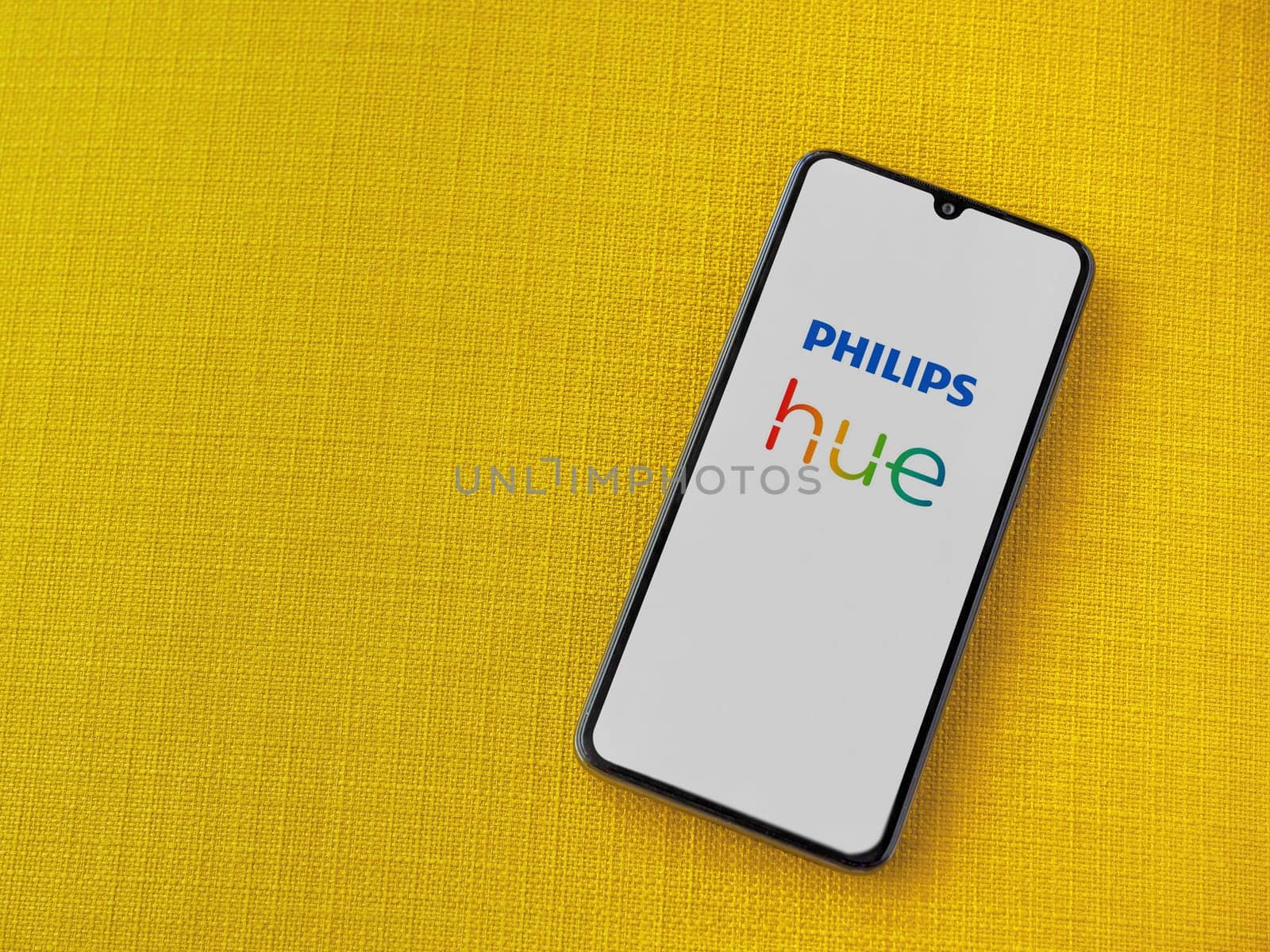 Lod, Israel - July 16,2023: Philips Hue app launch screen on smartphone on yellow fabric background. Top view flat lay with copy space.