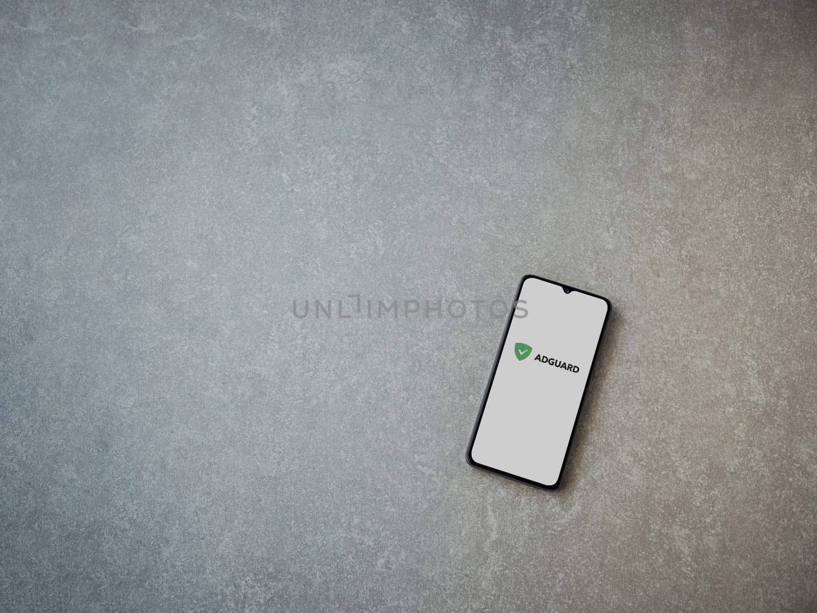 Lod, Israel - July 16,2023: AdGuard app launch screen on smartphone on ceramic stone background. Top view flat lay with copy space.