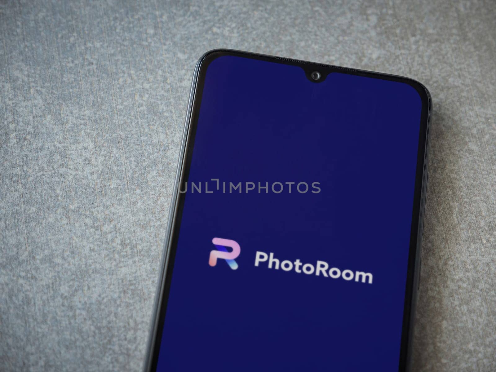 Lod, Israel - July 16,2023: PhotoRoom Studio Photo Editor app launch screen on smartphone on ceramic stone background.. Top view flat lay with copy space.