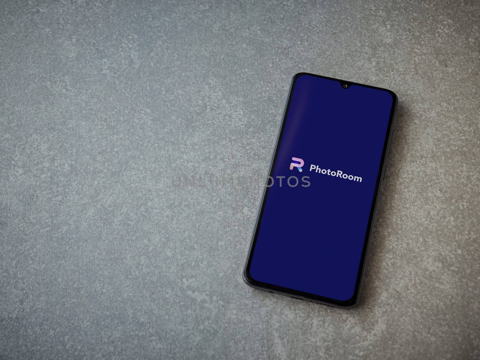 Lod, Israel - July 16,2023: PhotoRoom Studio Photo Editor app launch screen on smartphone on ceramic stone background.. Top view flat lay with copy space.