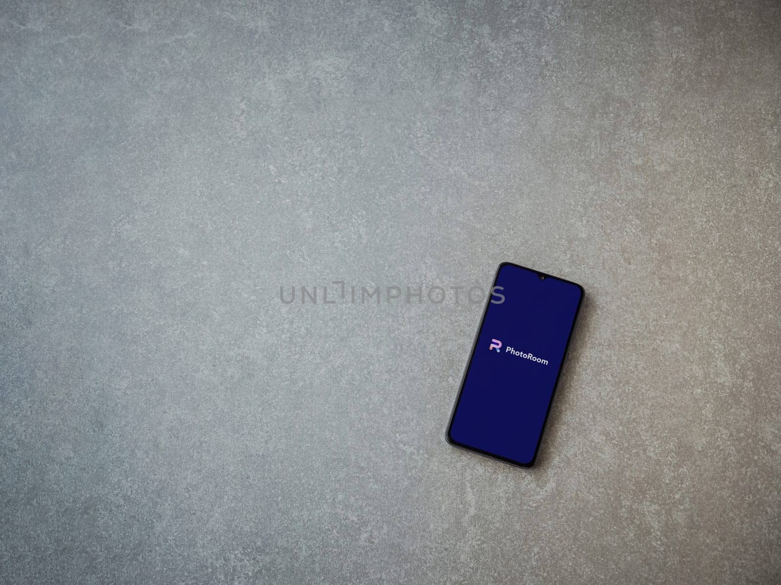 Lod, Israel - July 16,2023: PhotoRoom Studio Photo Editor app launch screen on smartphone on ceramic stone background.. Top view flat lay with copy space.